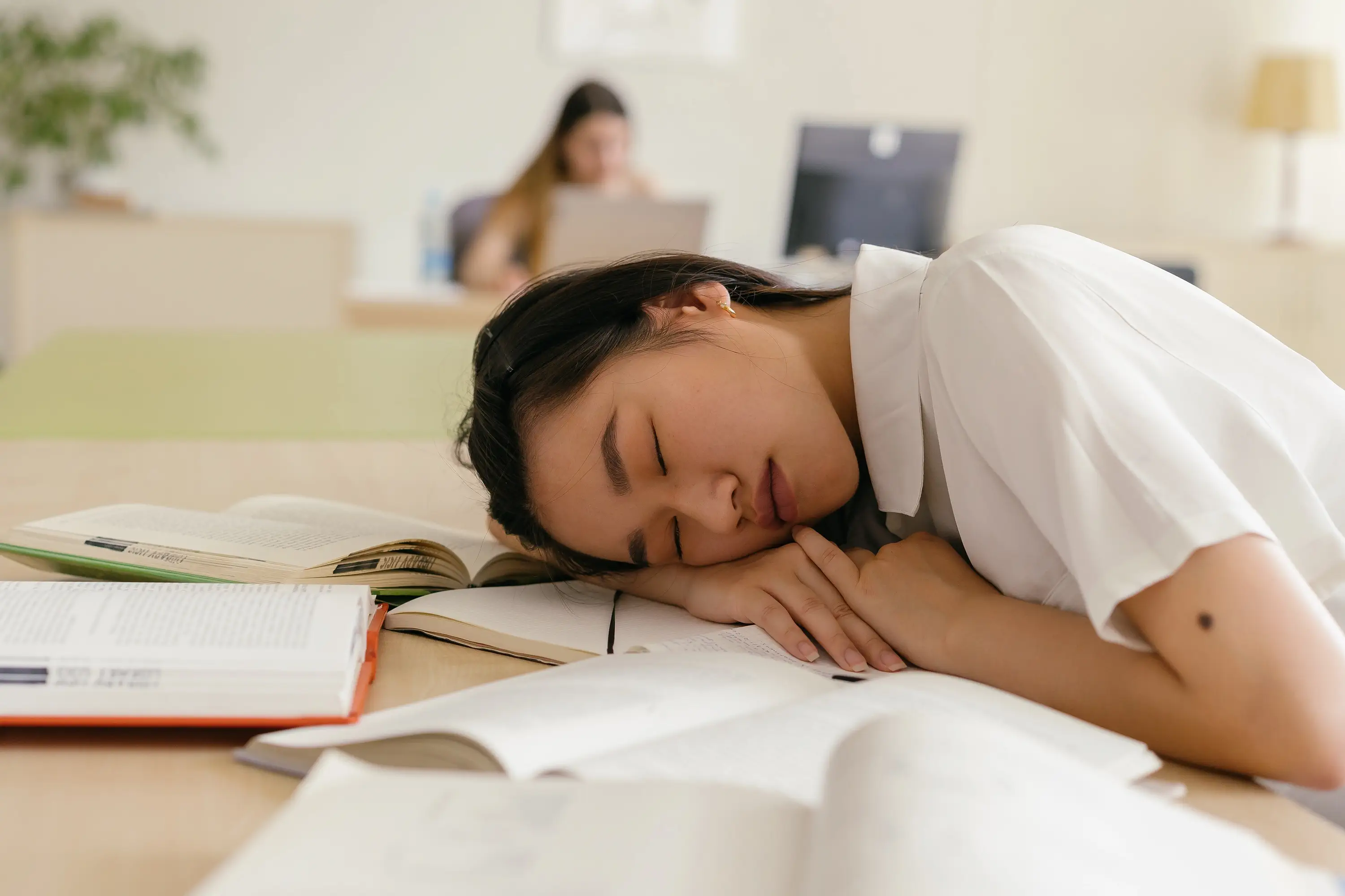 person at a desk sleeping on their arm